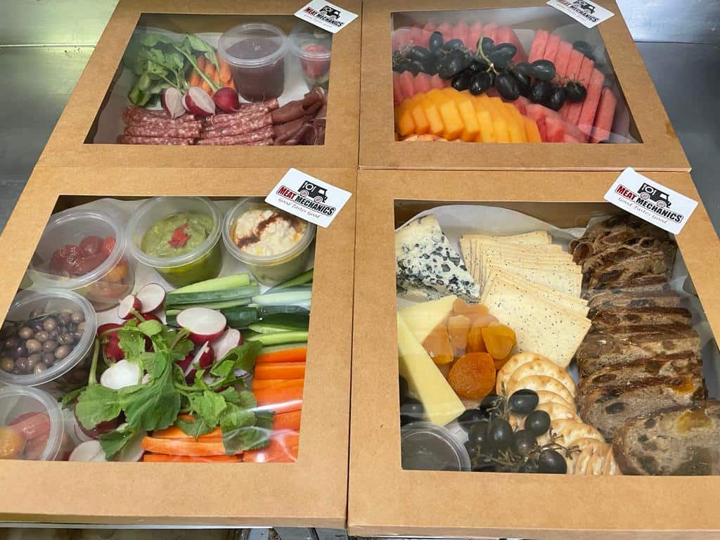 Artisan meat, cheese, and fruit platter boxes with assorted gourmet sides, ideal for events, gatherings, or gifts.