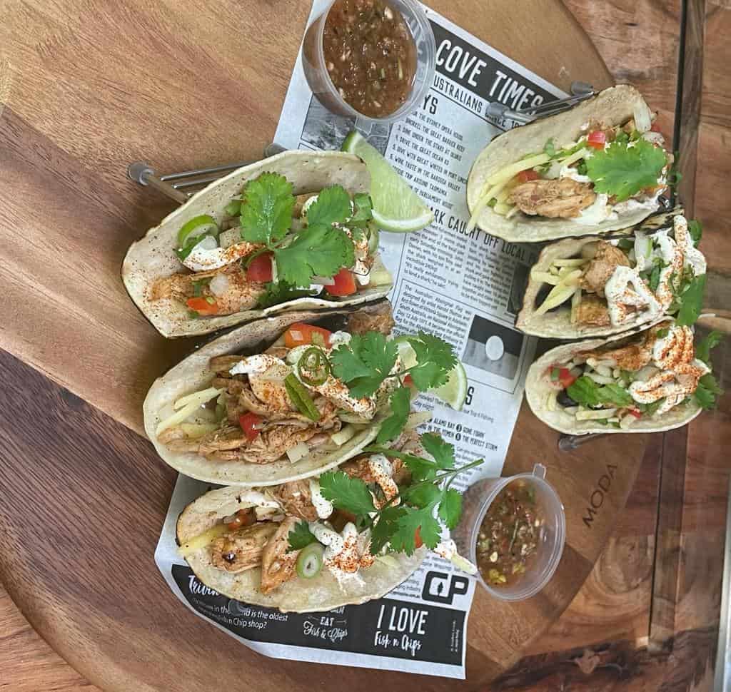 Delicious beef tacos with fresh toppings served on a wooden table with side salsa and lime wedge.