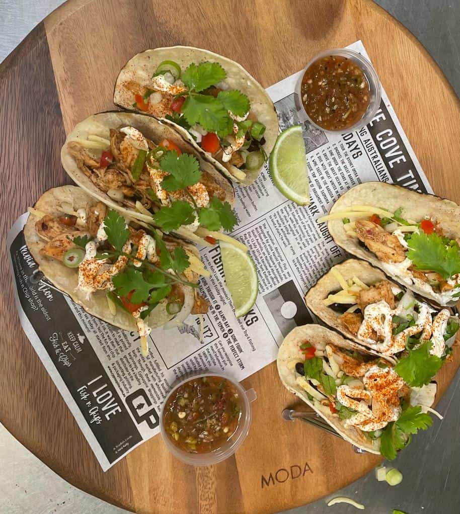 Delicious meat tacos topped with fresh herbs and served with wedges of lime and salsa.