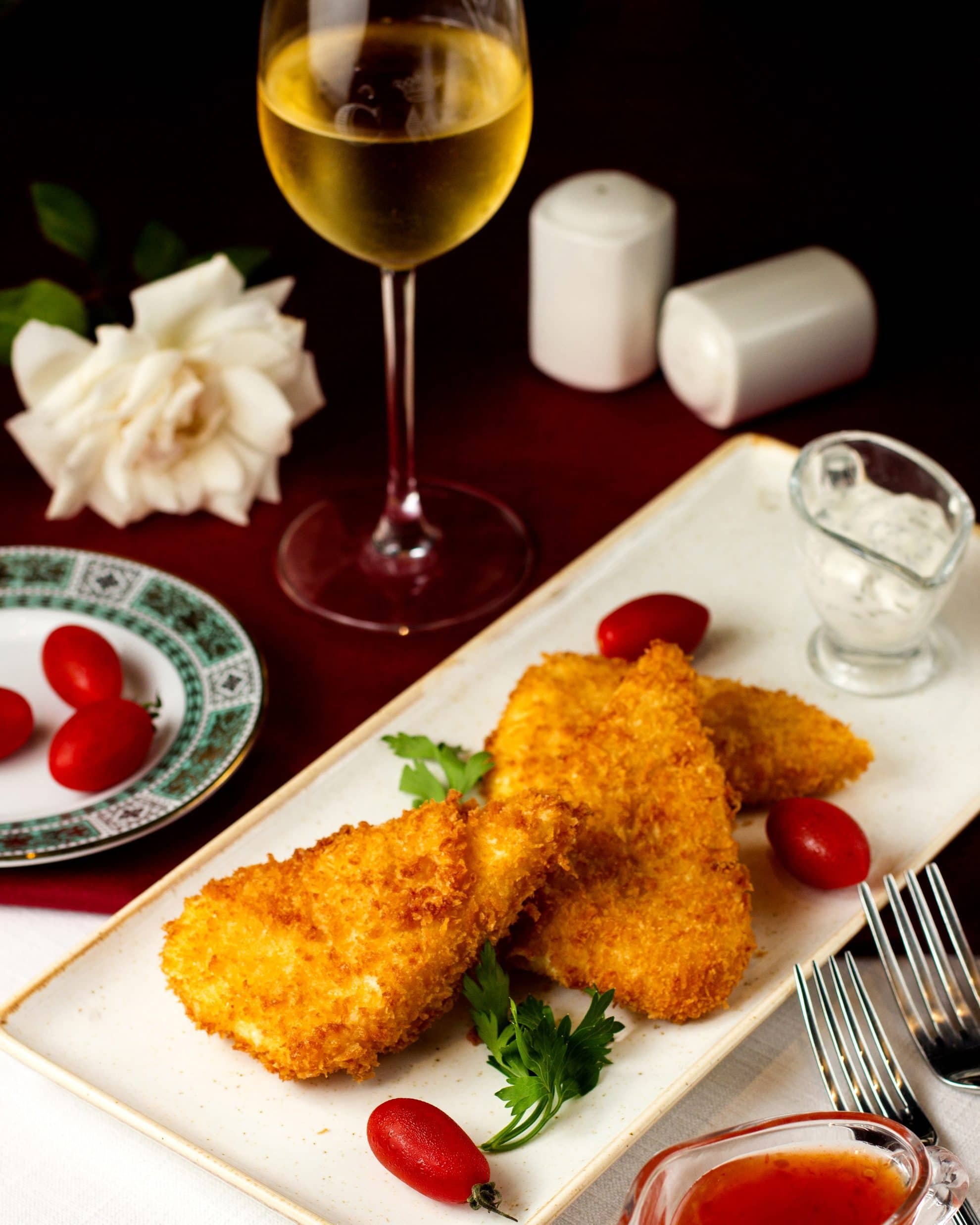Crispy breaded meat bites with creamy dipping sauce on newspaper page