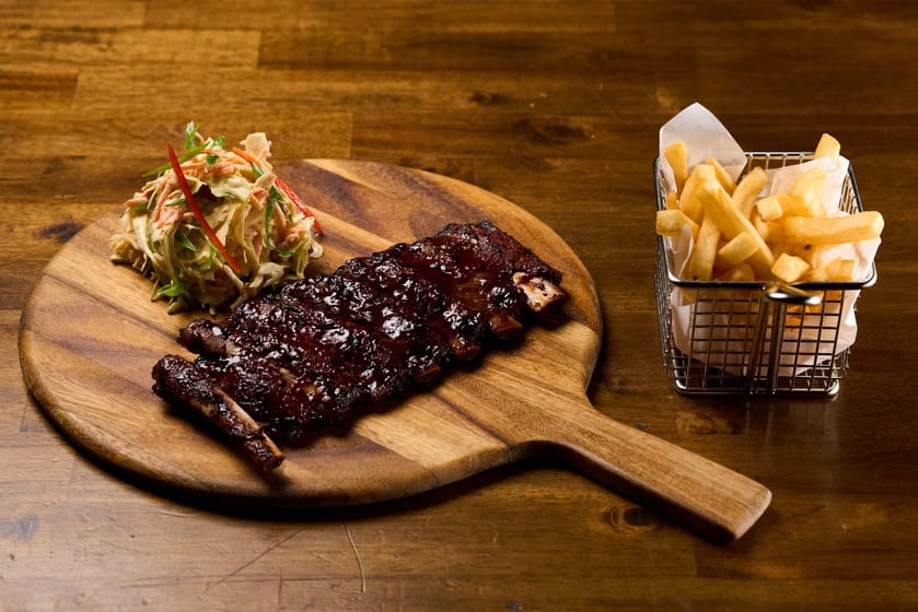 Tender barbecue ribs served with fresh coleslaw and crispy fries, perfect for meat lovers.
