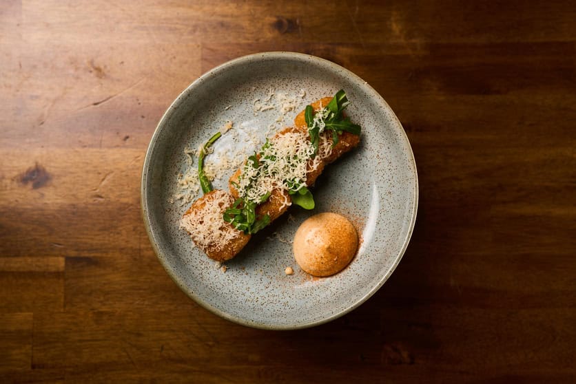 Gourmet meat dish from Meat Mechanics with fresh greens and crispy toppings.