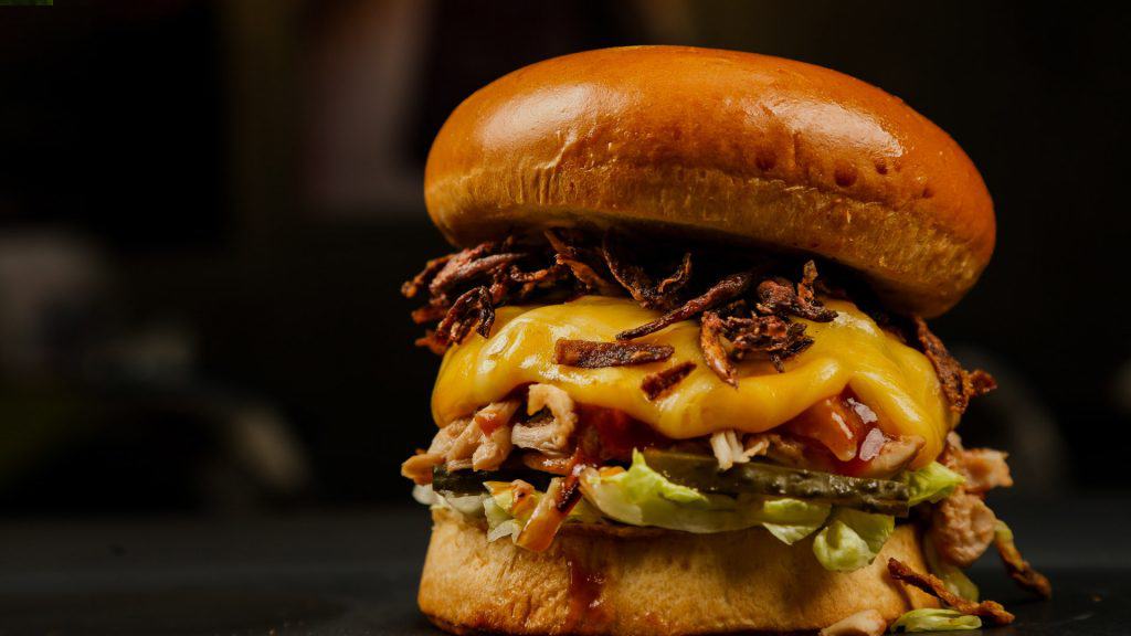 Juicy cheeseburger with smoked brisket, cheddar, crispy onions, and fresh vegetables on toasted bun.